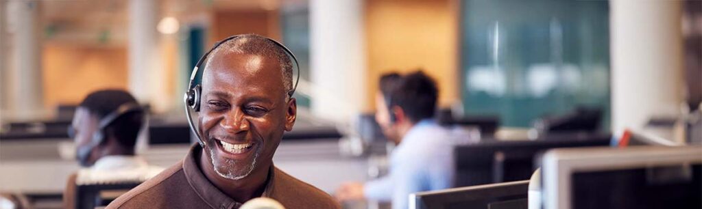 A smiling professional wearing a headset, representing customer support during VoIP consulting sessions, as offered by Chambers Advisory Group