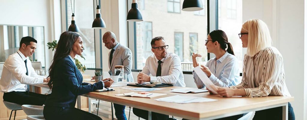 Business professionals having a lively discussion in a meeting setting, emphasizing the collaborative nature of Chambers Advisory Group's Telecom Expense Audit process.